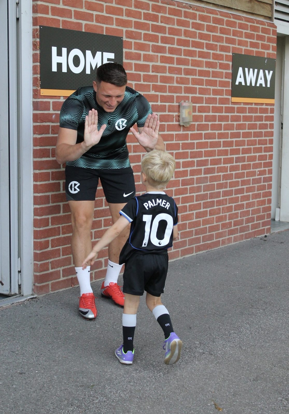 A coach high-fiving a young player on arrival at a Bournemouth Ballers summer camp