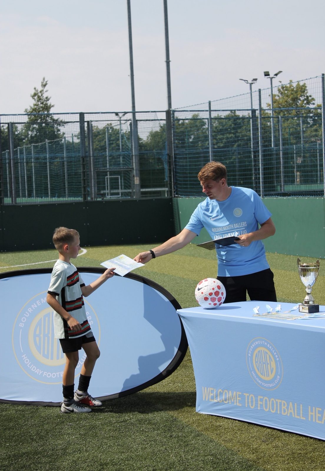 A young player collecting his certificate at the end-of-camp presentation table